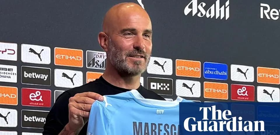 Entrenador sosteniendo camiseta de Manchester City en rueda de prensa