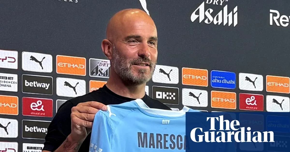 Entrenador sosteniendo camiseta de Manchester City en rueda de prensa
