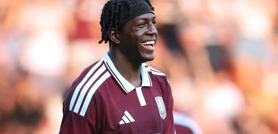 Jugador sonriendo con camiseta granate en el campo