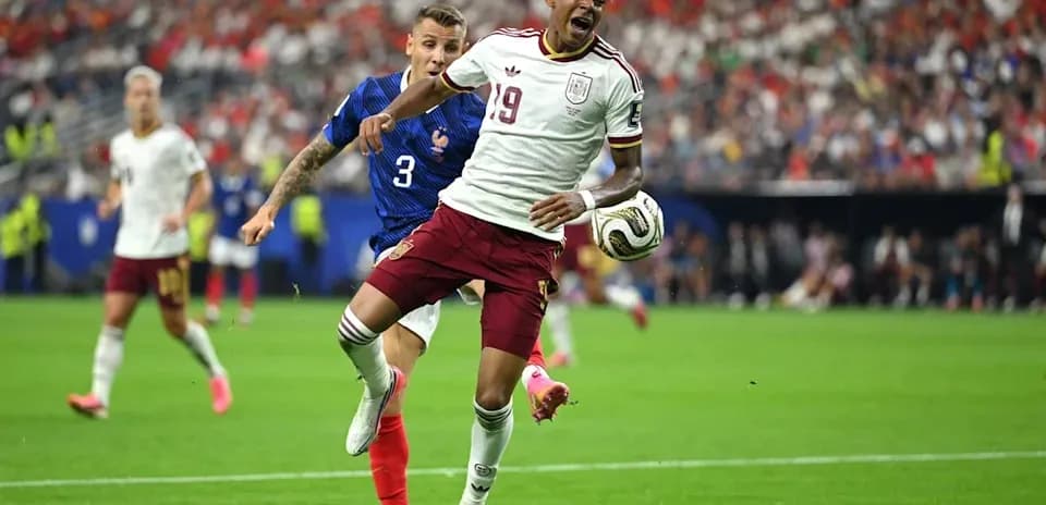 Jugador español esquivando a defensor francés durante partido