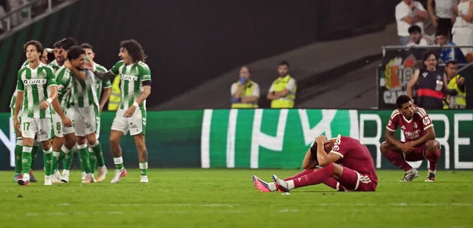 Jugadores de Betis celebrando tras gol, rival caído