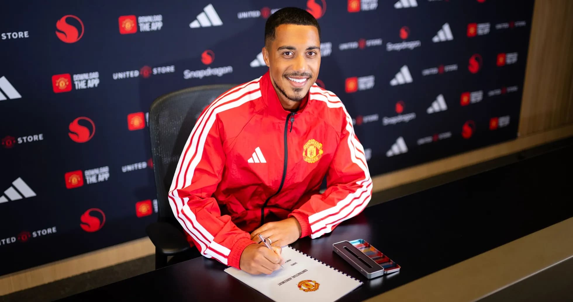 Jugador firmando contrato en mesa de prensa