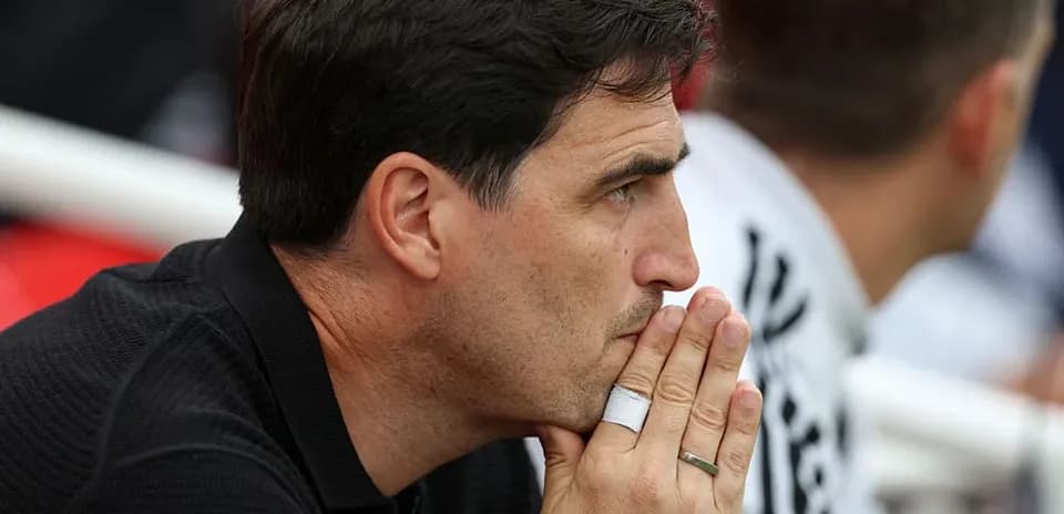 Entrenador observando el partido con expresión pensativa
