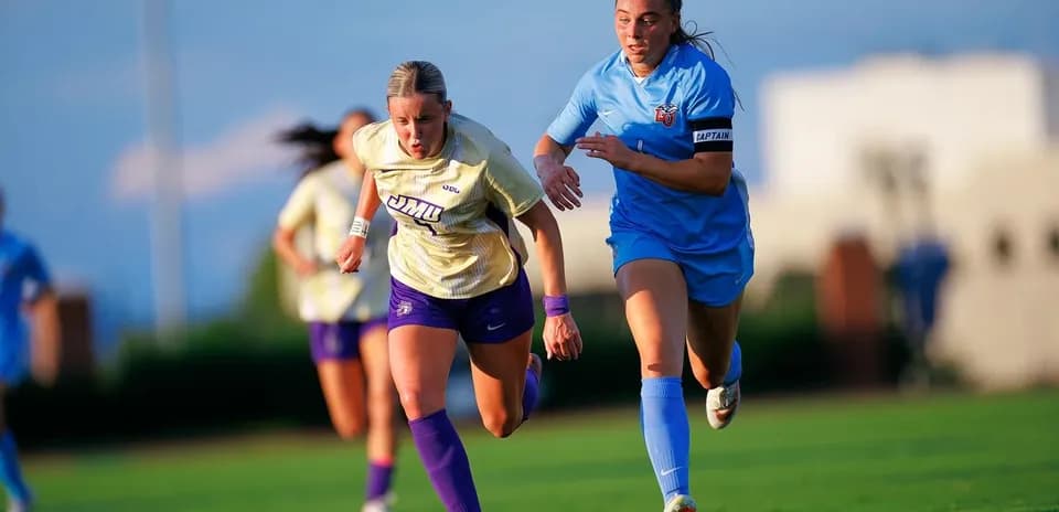 Jugadora de JMU corriendo con rival de LU