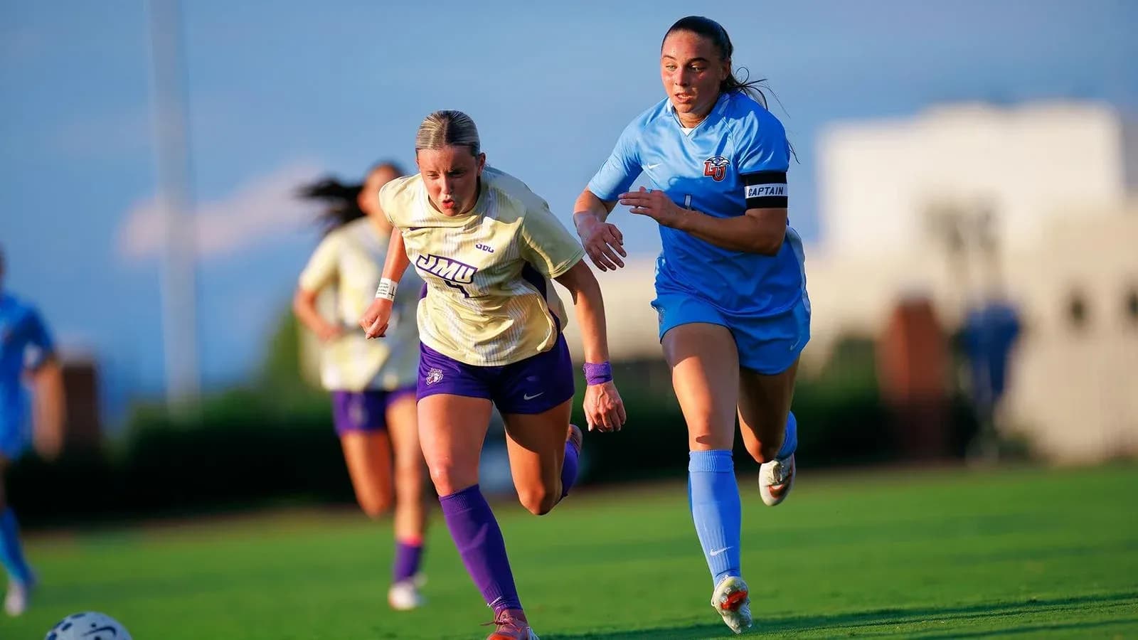 Jugadora de JMU corriendo con rival de LU