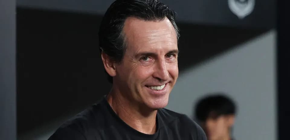 Entrenador sonriendo en el banquillo durante partido