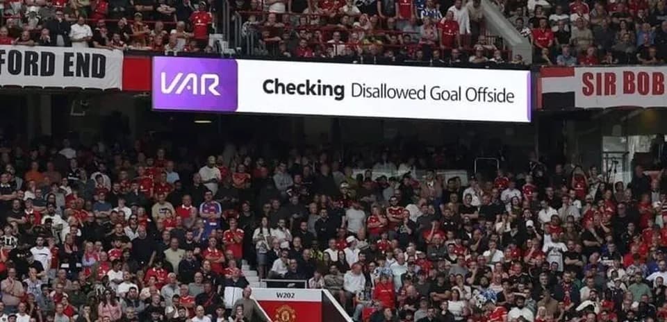 Aficionados observando pantalla de VAR en estadio