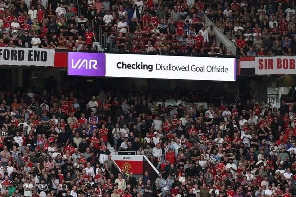 Aficionados observando pantalla de VAR en estadio