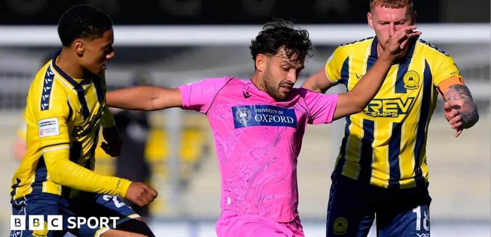 Jugador en camiseta rosa rodeado por dos oponentes