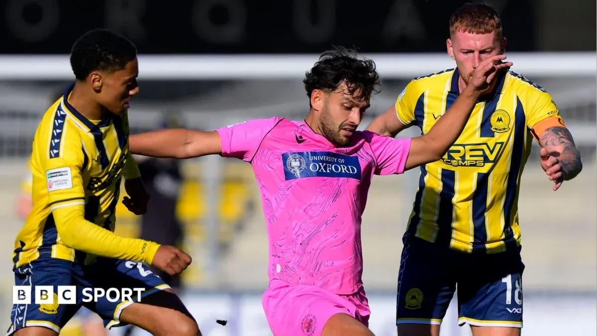 Jugador en camiseta rosa rodeado por dos oponentes