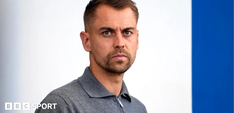 Hombre con camiseta gris frente a fondo blanco y azul