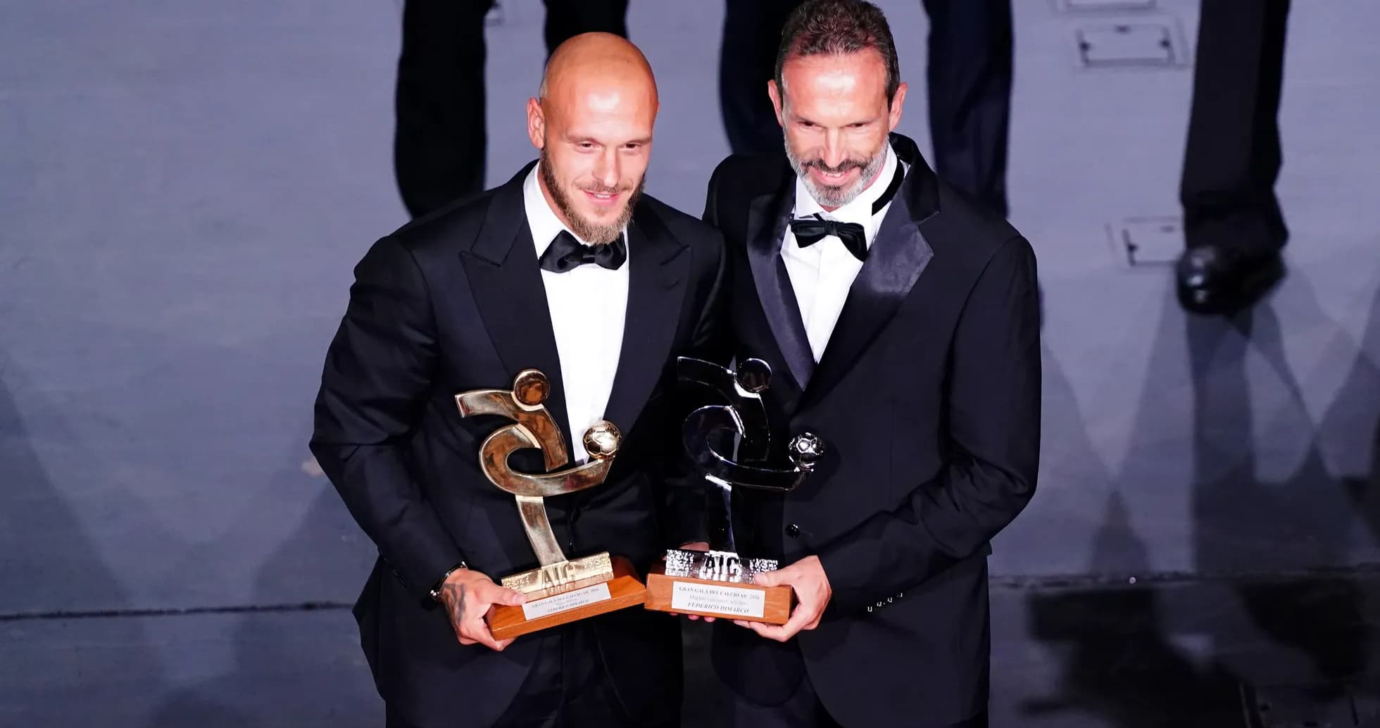 Dos hombres con trofeos en ceremonia de premiación