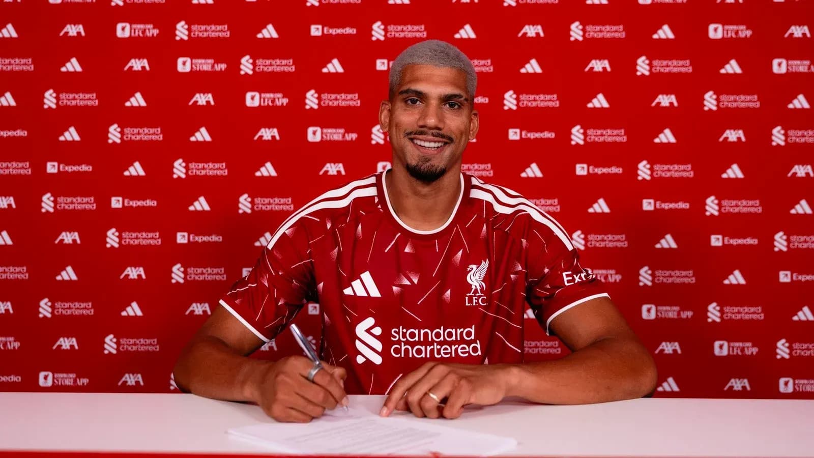 Jugador firmando contrato con camiseta de Liverpool