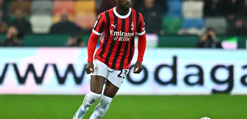 Jugador de AC Milan corriendo con balón en el campo
