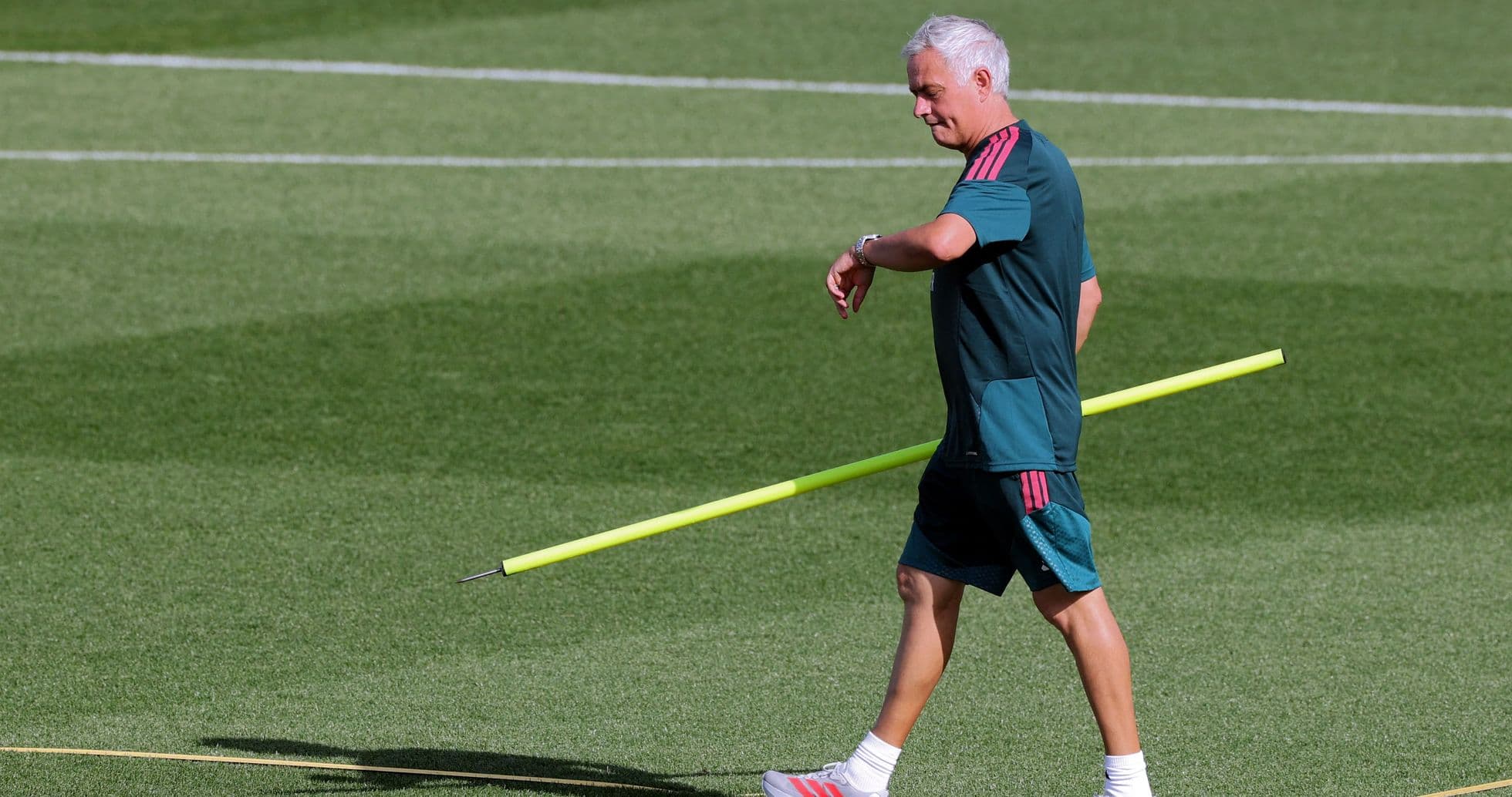 Entrenador caminando con un palo amarillo en el campo