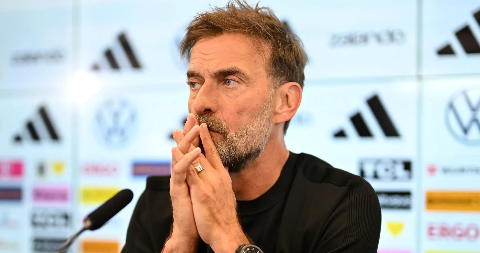 Entrenador en conferencia de prensa, manos entrelazadas