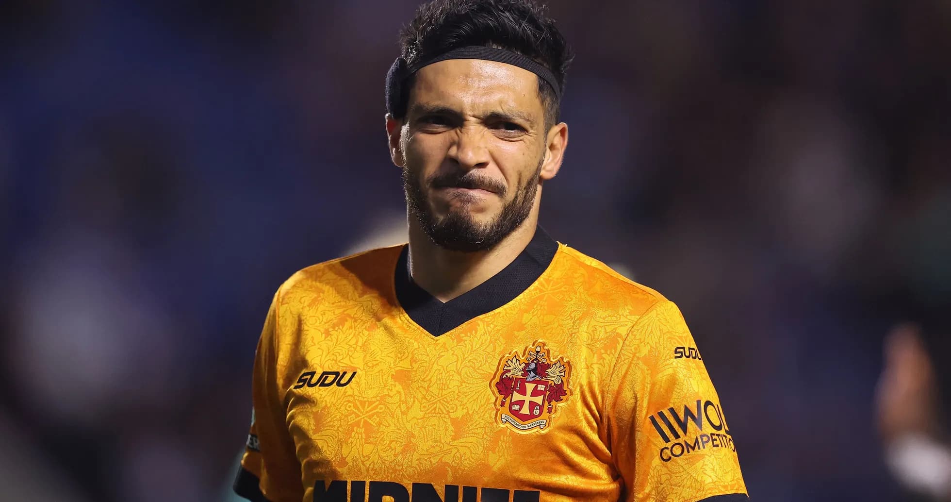 Jugador con camiseta naranja sonriendo en el campo