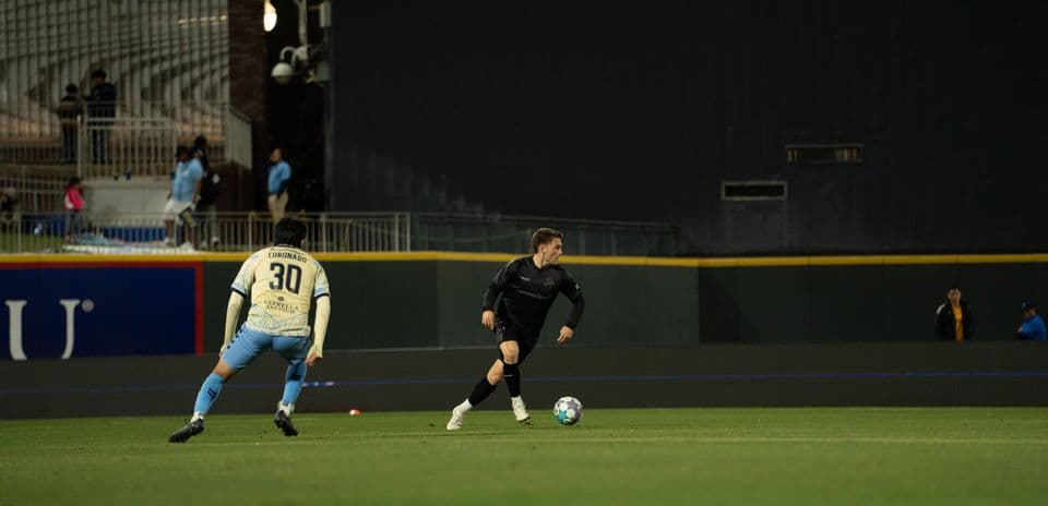 Jugador corriendo con el balón en el campo