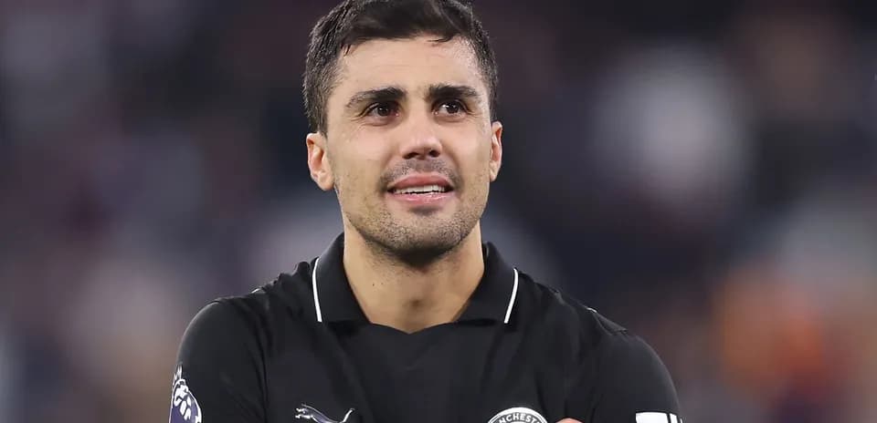 Jugador de fútbol con camiseta negra sonriendo en el campo