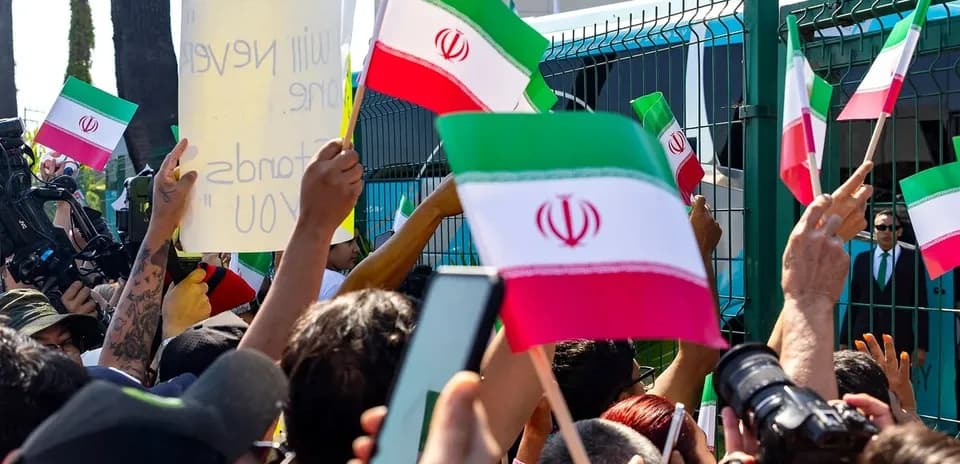 Multitud sosteniendo banderas de Irán durante protesta