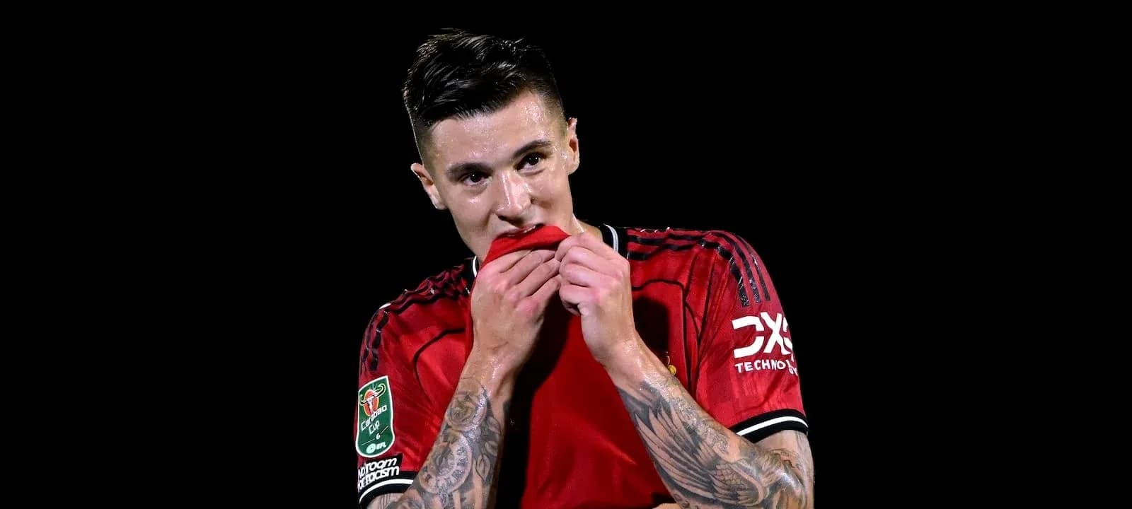Jugador de fútbol sosteniendo su camiseta roja
