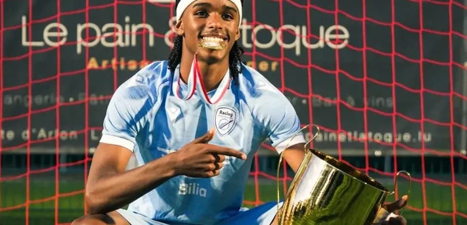 Jugador sosteniendo un trofeo frente a la portería