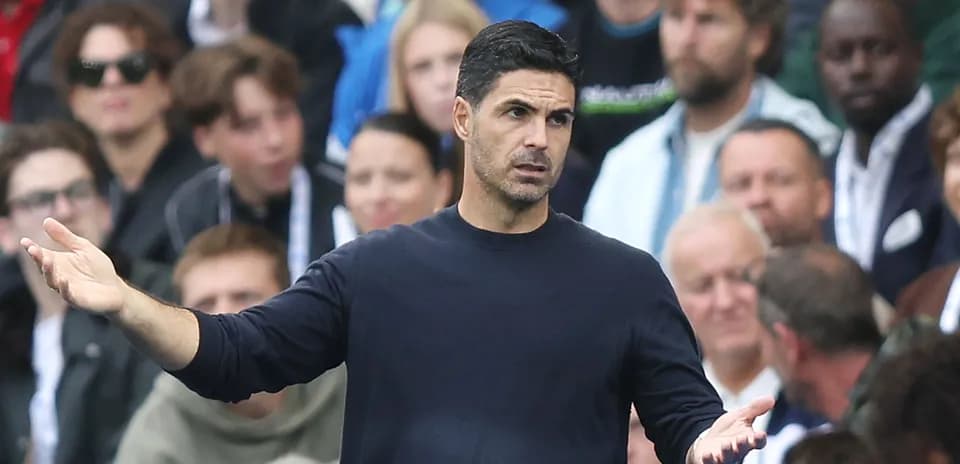 Entrenador gesticulando durante el partido con aficionados detrás
