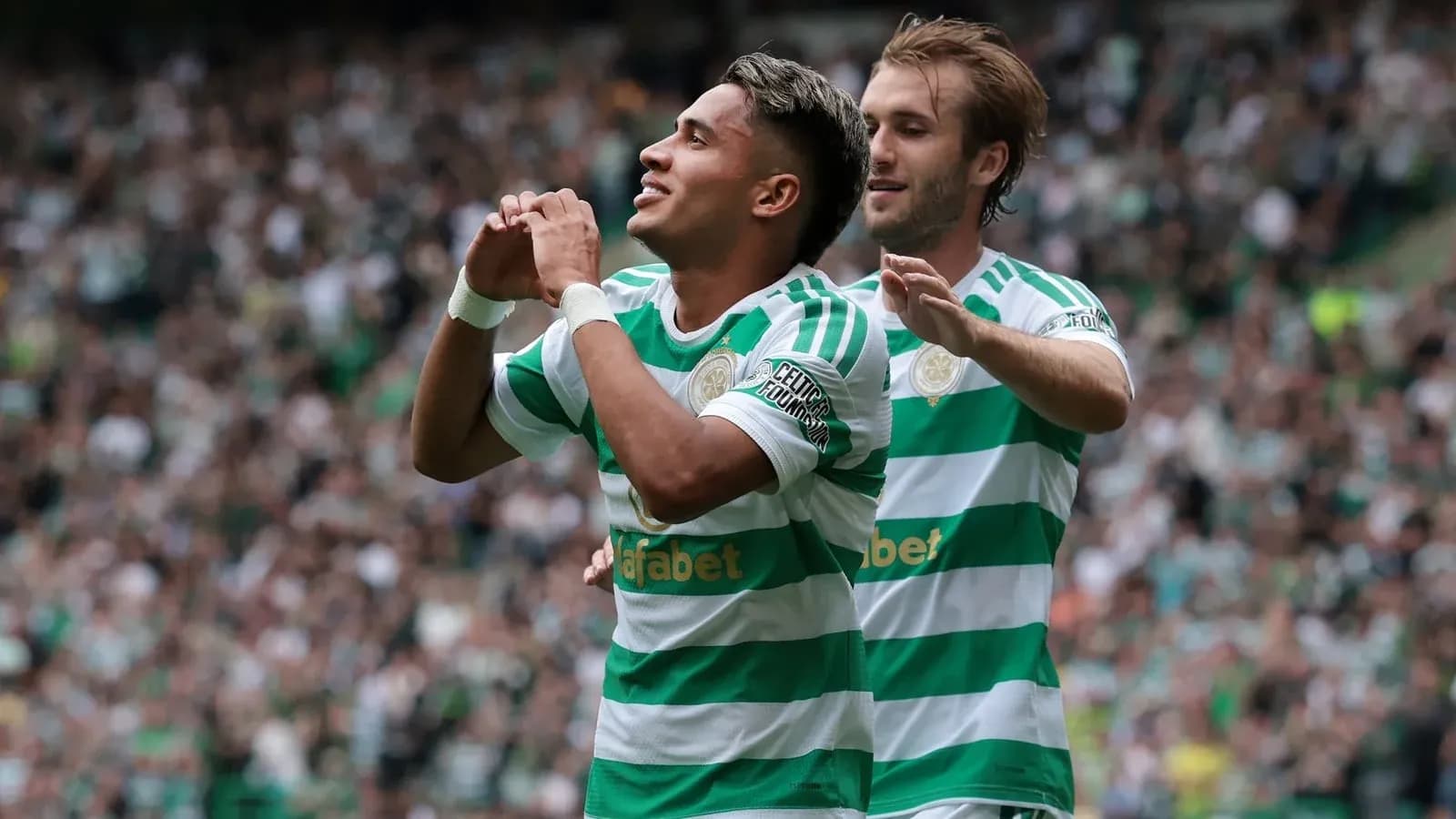 Jugador celebrando un gol con compañero en estadio
