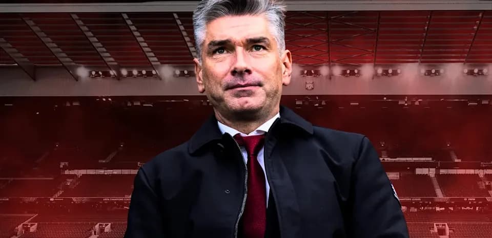 Entrenador posando frente a un estadio de fútbol