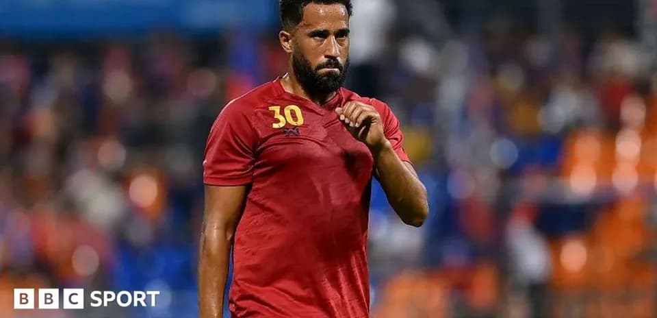 Jugador con camiseta roja caminando por el campo