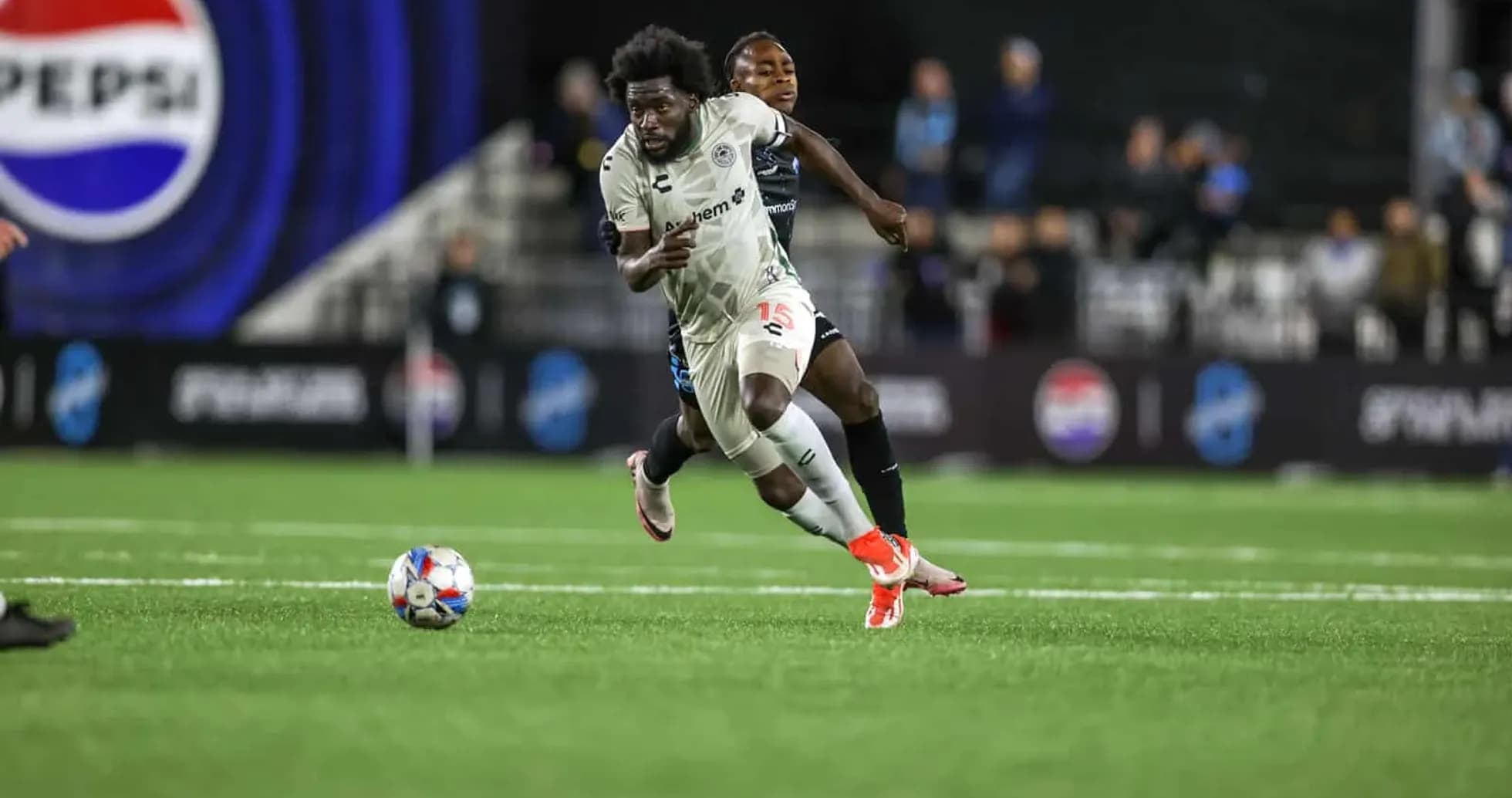 Jugador corriendo con el balón en partido de fútbol
