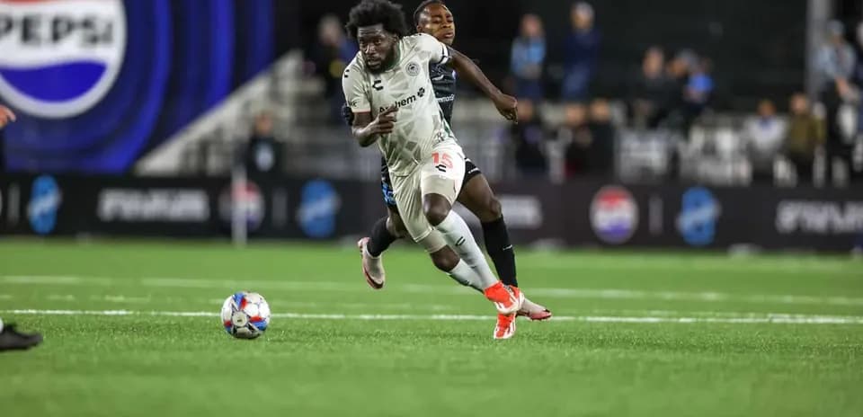Jugador corriendo con el balón en partido de fútbol