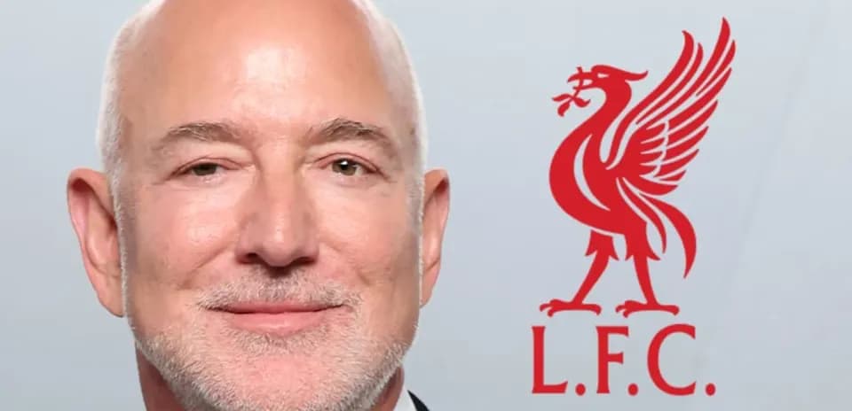 Hombre sonriente con logo de Liverpool detrás