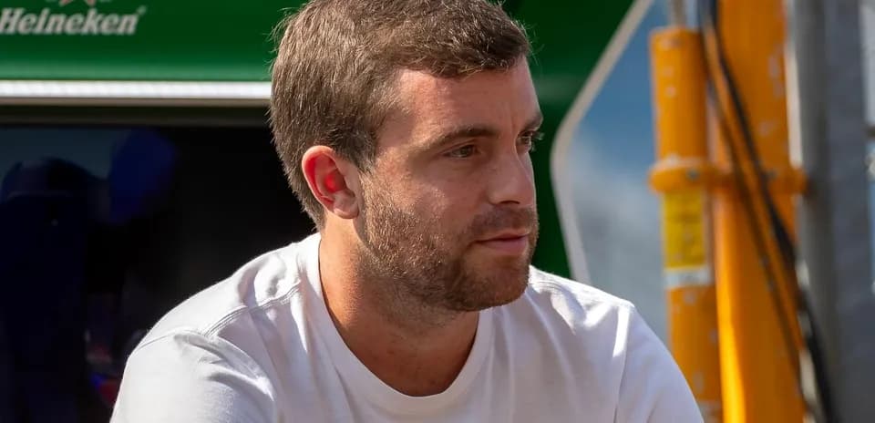 Hombre sentado con camiseta blanca en el paddock