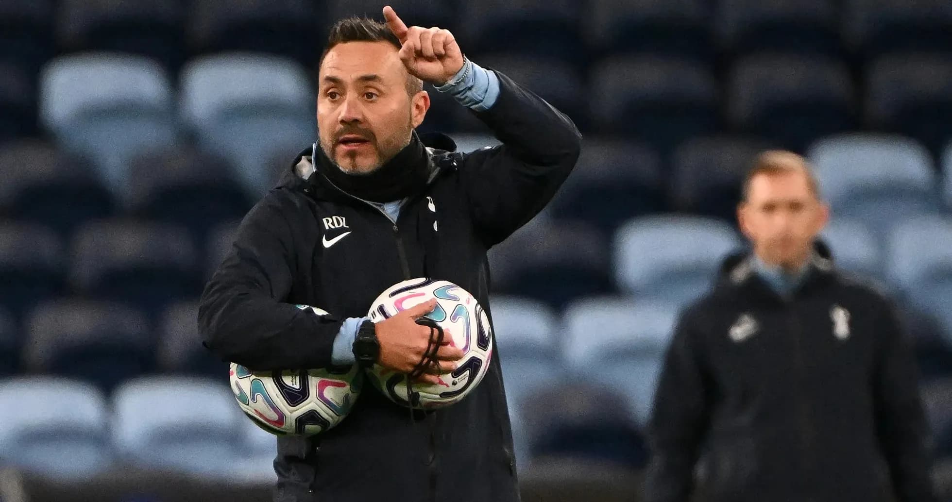 Entrenador dando instrucciones con balones en brazos