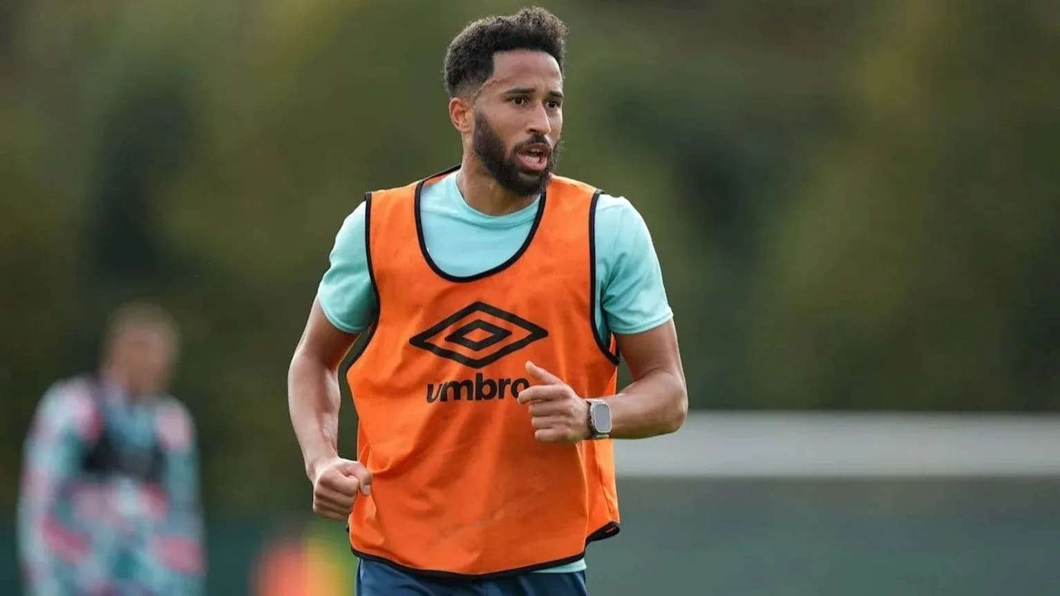 Jugador entrenando con chaleco naranja en el campo