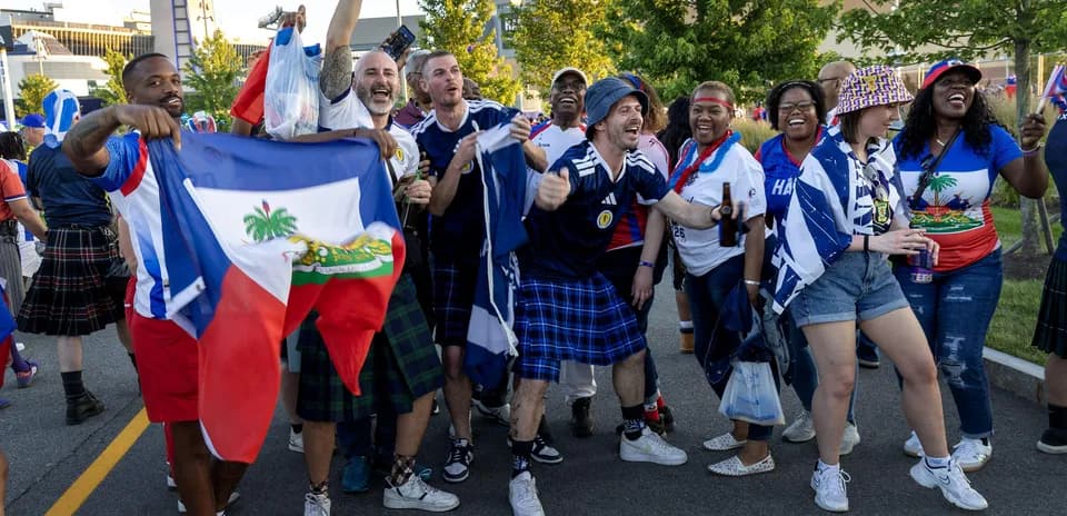 Aficionados celebrando con banderas de Haití y Escocia