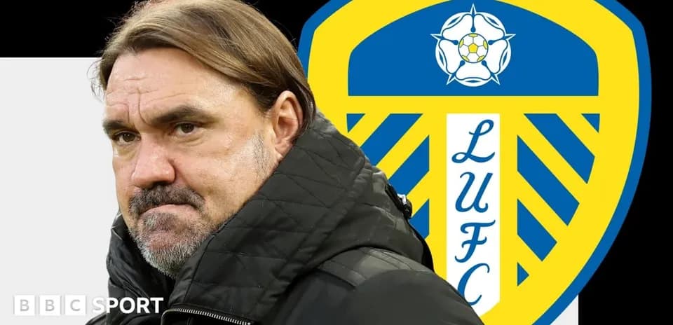 Entrenador de pie frente al escudo de Leeds United