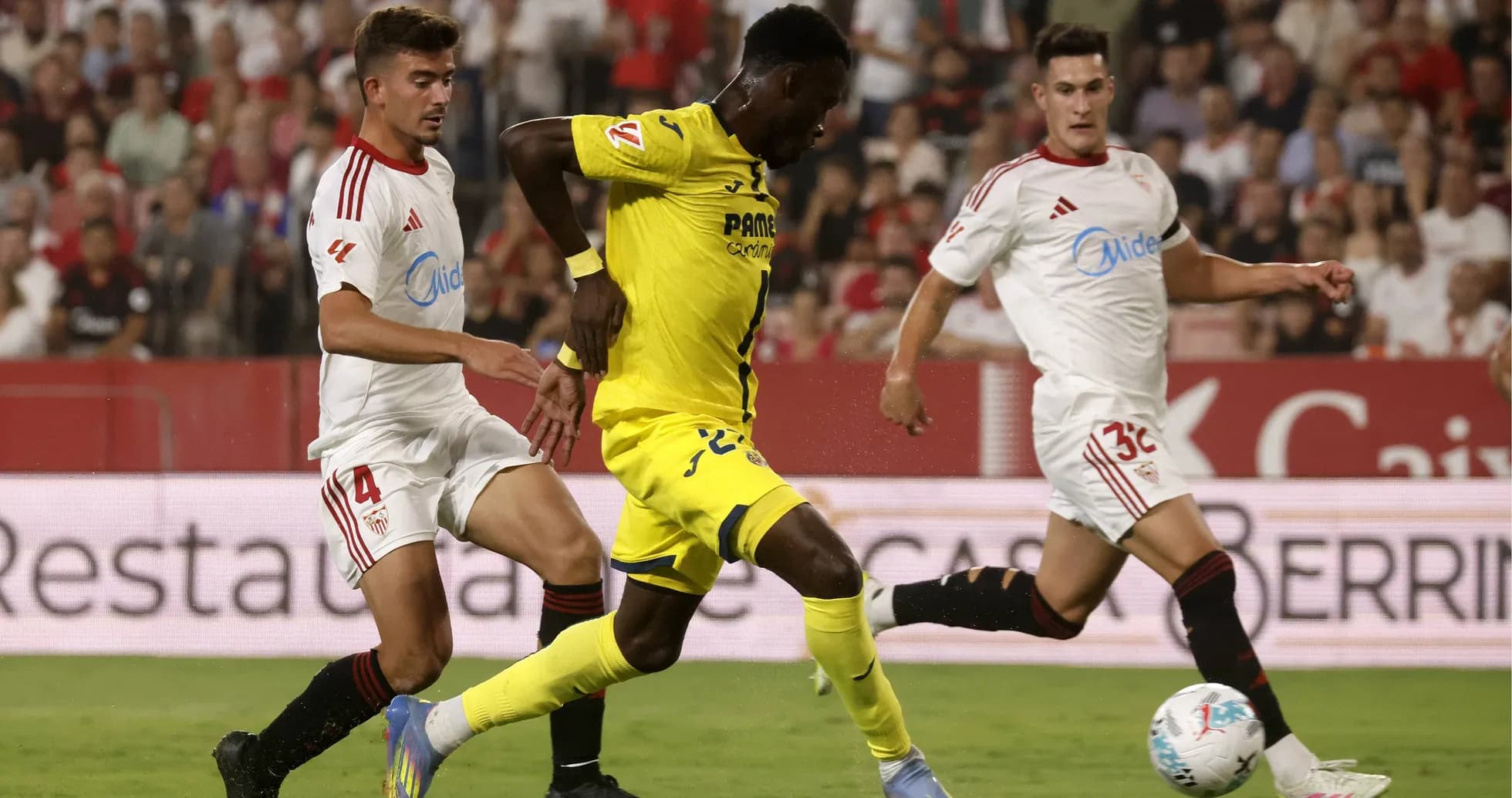 Jugador de Villarreal superando a defensores de Sevilla