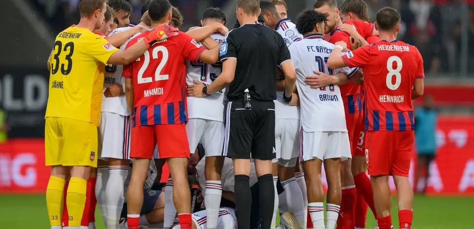 Jugadores de ambos equipos rodeando a un compañero caído