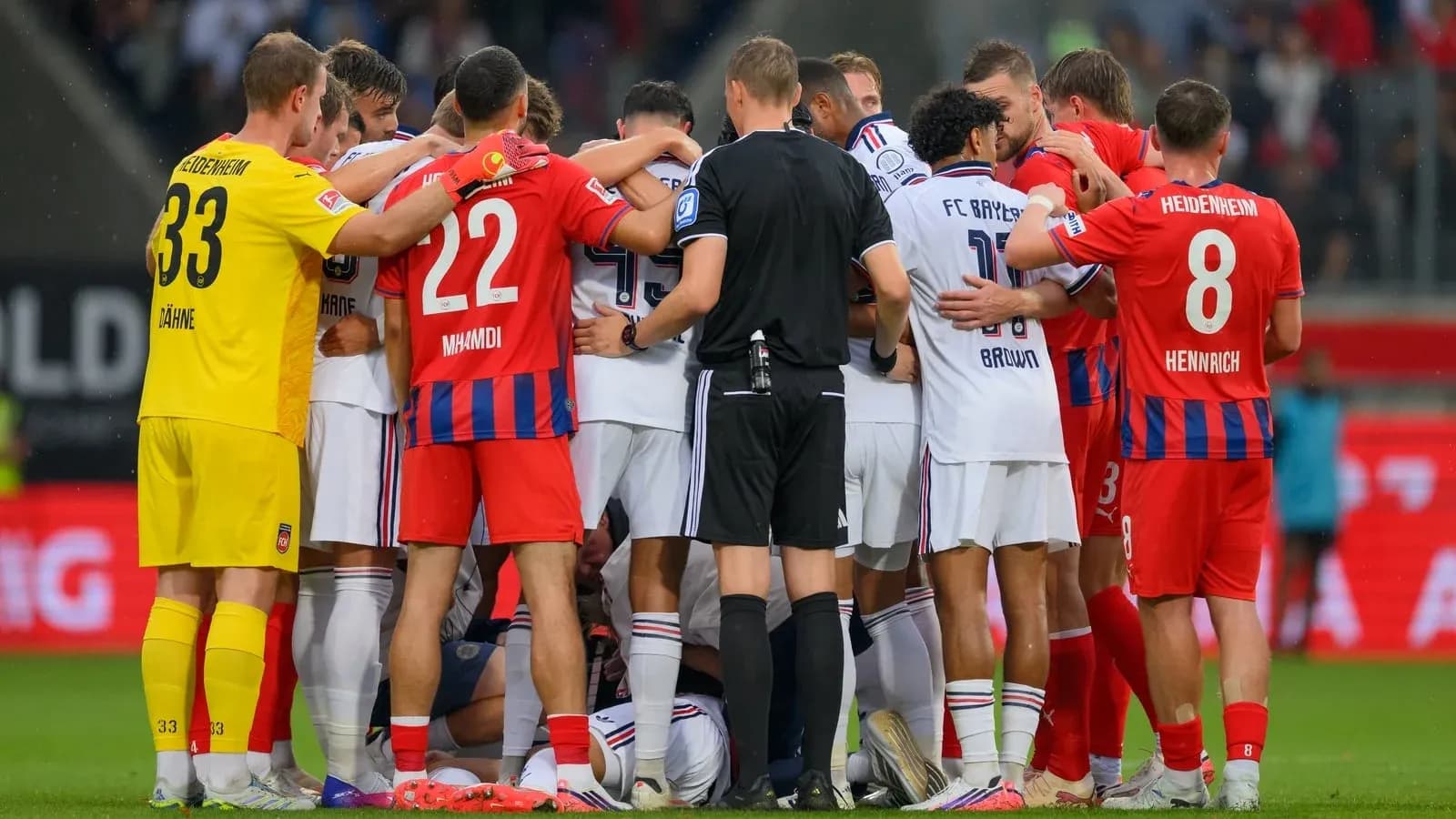 Jugadores de ambos equipos rodeando a un compañero caído