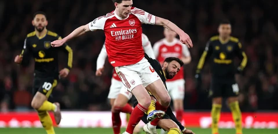 Jugador de Arsenal saltando sobre oponente caído