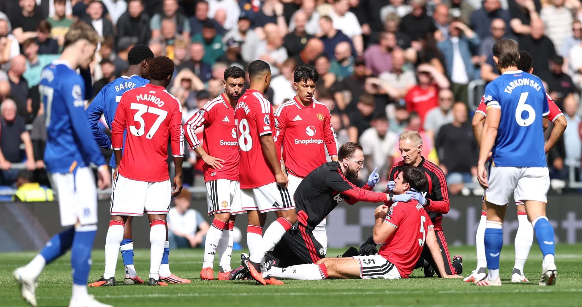 Jugadores de Manchester United rodeando a jugador lesionado