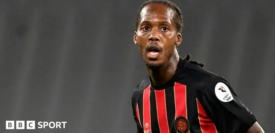 Jugador de fútbol en acción con camiseta roja y negra