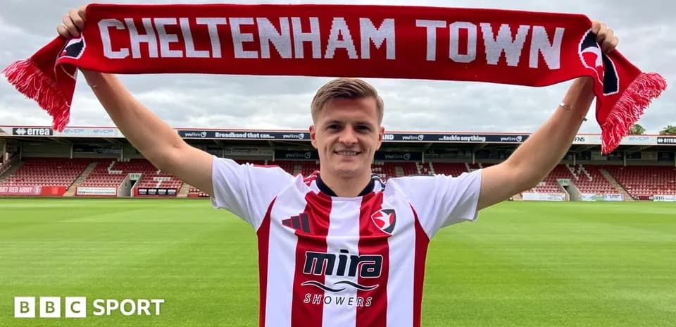 Jugador sosteniendo bufanda de Cheltenham Town en el estadio