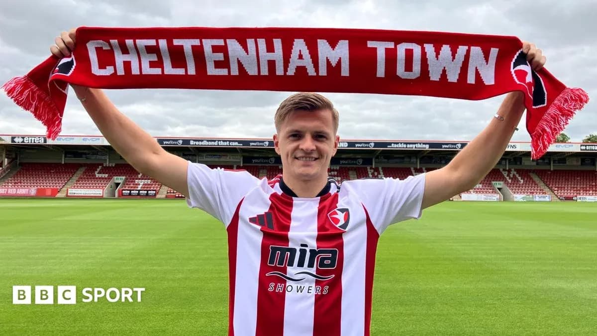 Jugador sosteniendo bufanda de Cheltenham Town en el estadio