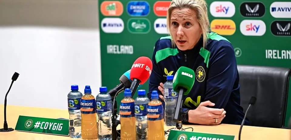 Entrenadora en rueda de prensa con micrófonos y botellas