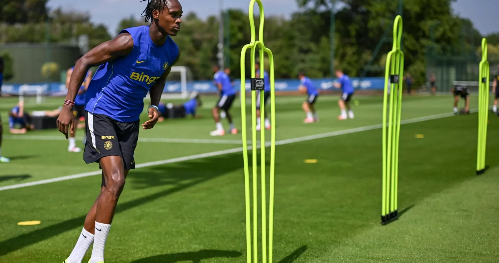 Jugador entrenando en campo con conos de práctica Jugador entrenando en campo con conos de práctica
