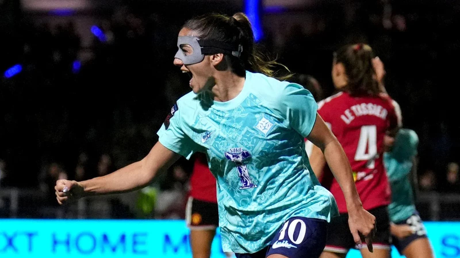 Jugadora celebrando un gol con una máscara en partido Jugadora celebrando un gol con una máscara en partido