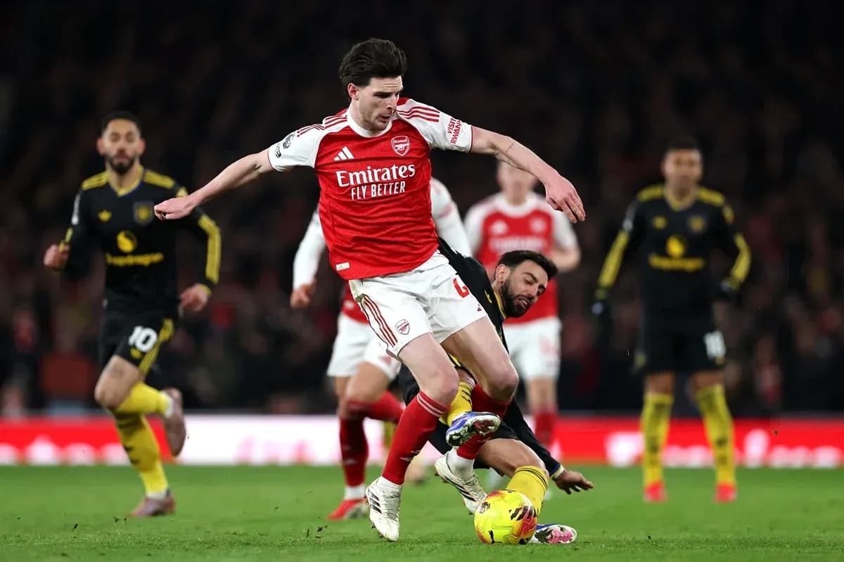 Jugador de Arsenal saltando sobre oponente caído Jugador de Arsenal saltando sobre oponente caído